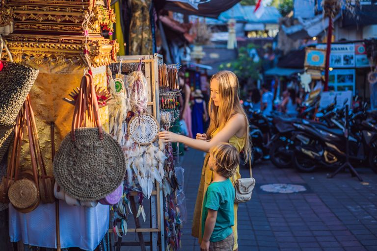 Mum And Son Travelers Choose Souvenirs In The Market At Ubud In Bali, Indonesia