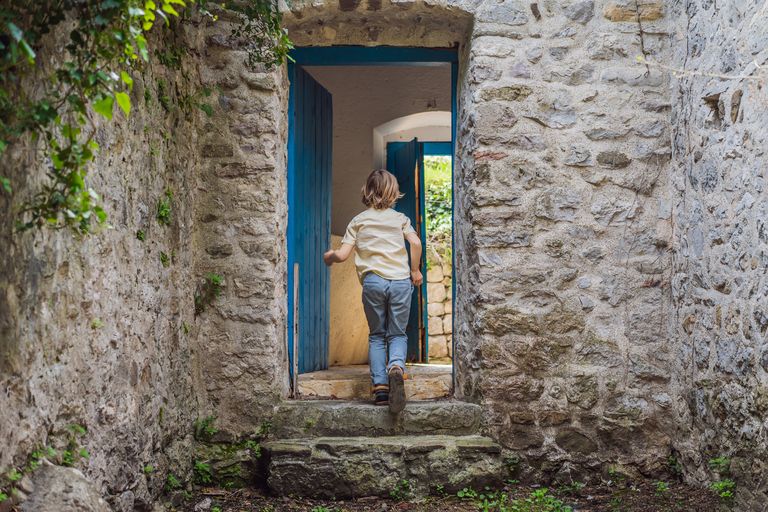 Child walks through blue door of an old building